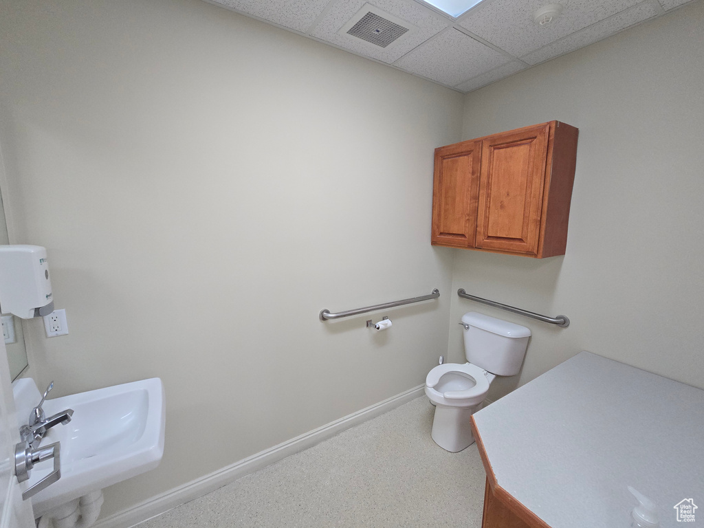 Bathroom featuring a drop ceiling, toilet, and sink