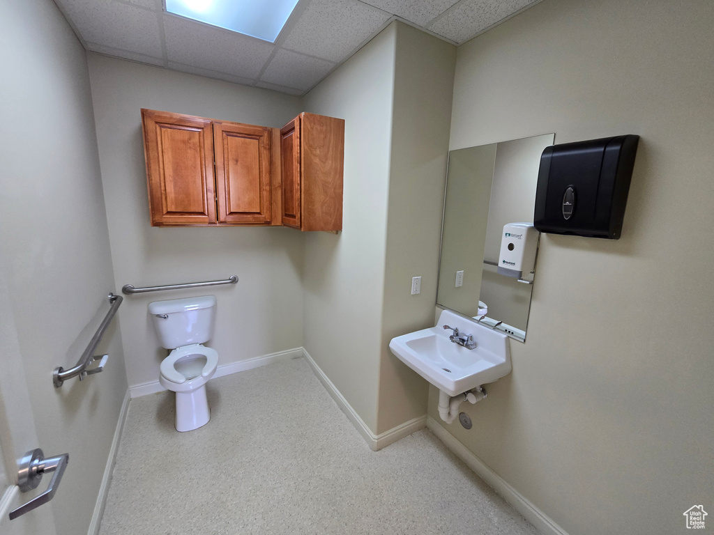 Bathroom featuring a drop ceiling, toilet, and sink