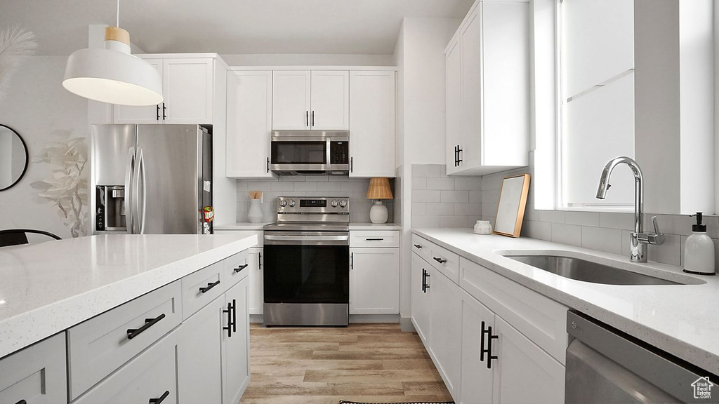 Kitchen featuring sink, stainless steel appliances, tasteful backsplash, and light hardwood / wood-style flooring