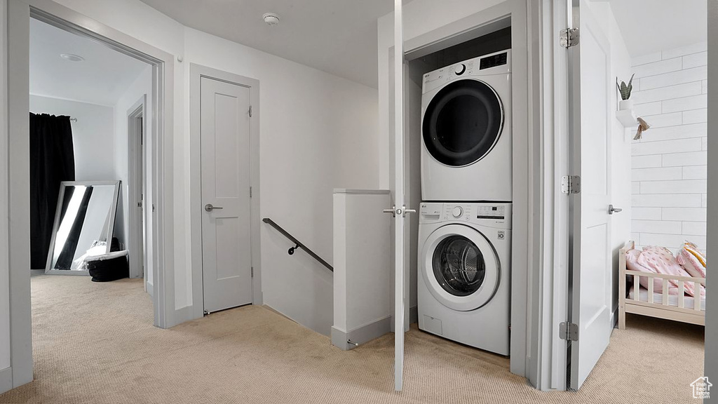 Laundry area with stacked washer / dryer and light carpet