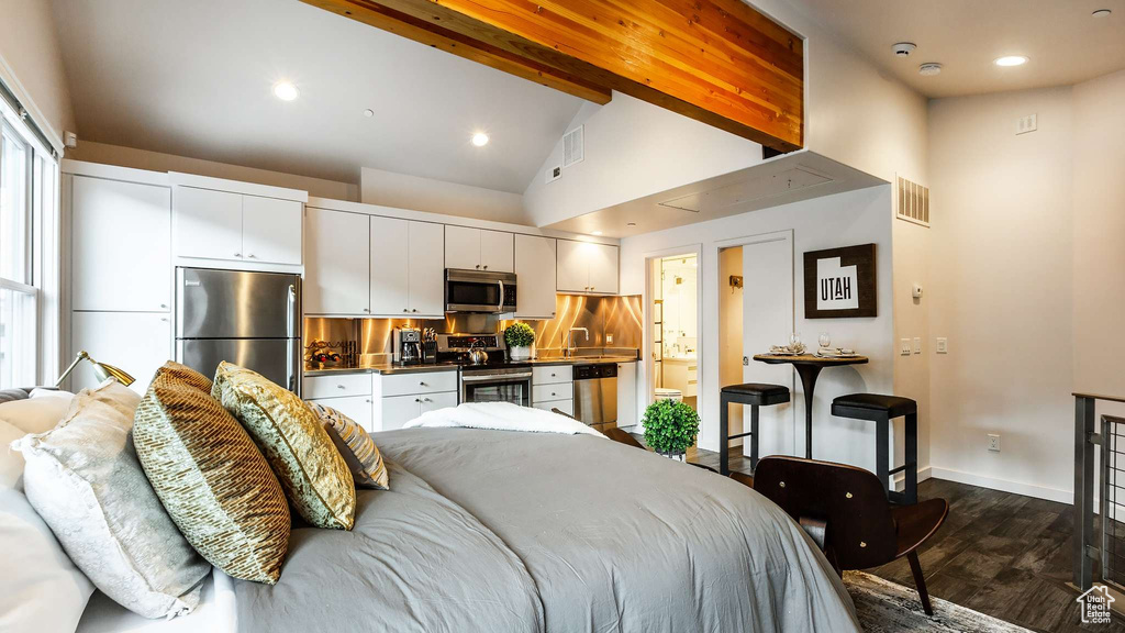 Bedroom featuring dark wood-type flooring, stainless steel fridge, high vaulted ceiling, and beam ceiling