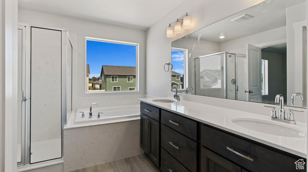 Bathroom featuring hardwood / wood-style floors, independent shower and bath, and double sink vanity