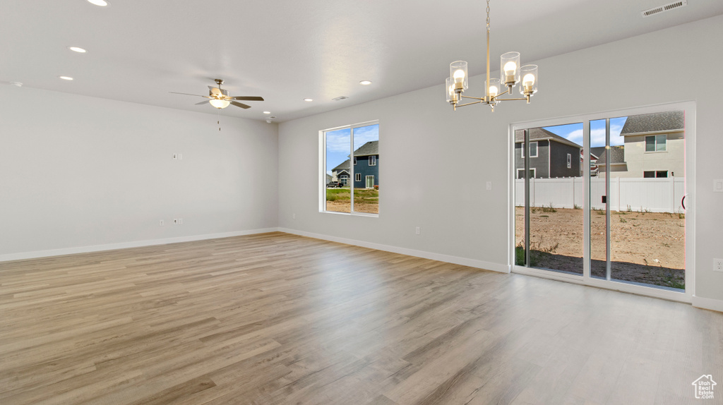 Empty room featuring light hardwood / wood-style flooring and ceiling fan with notable chandelier