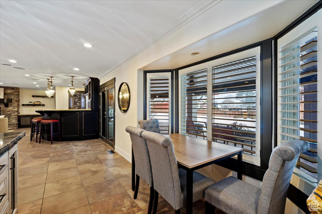 Tiled dining room featuring ornamental molding, indoor bar, and a wealth of natural light