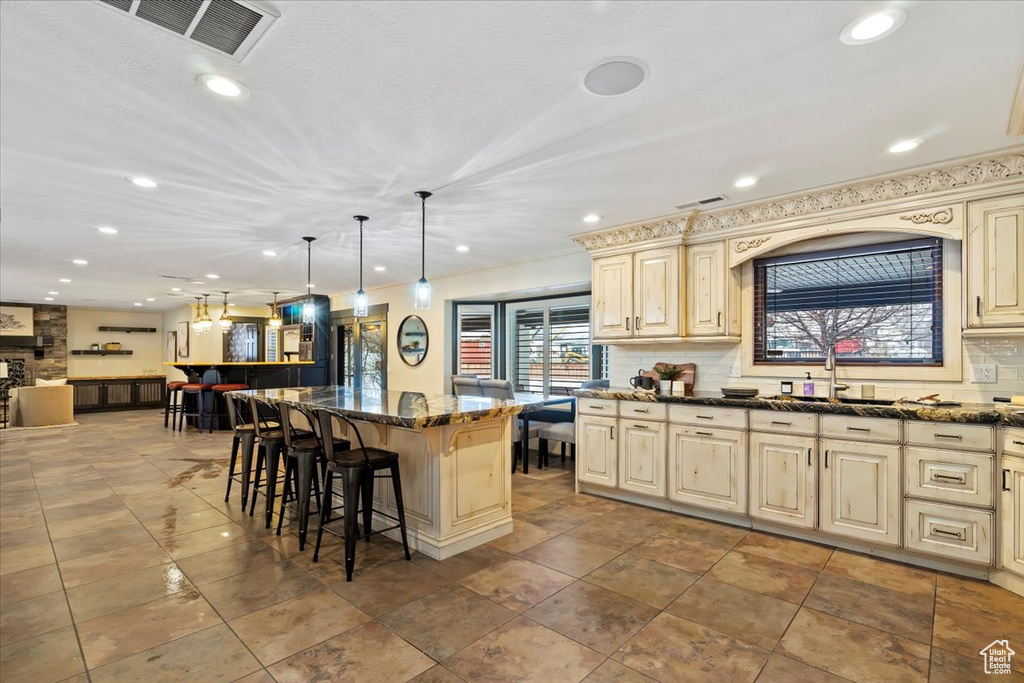 Kitchen with a kitchen breakfast bar, light tile floors, a center island, and decorative light fixtures