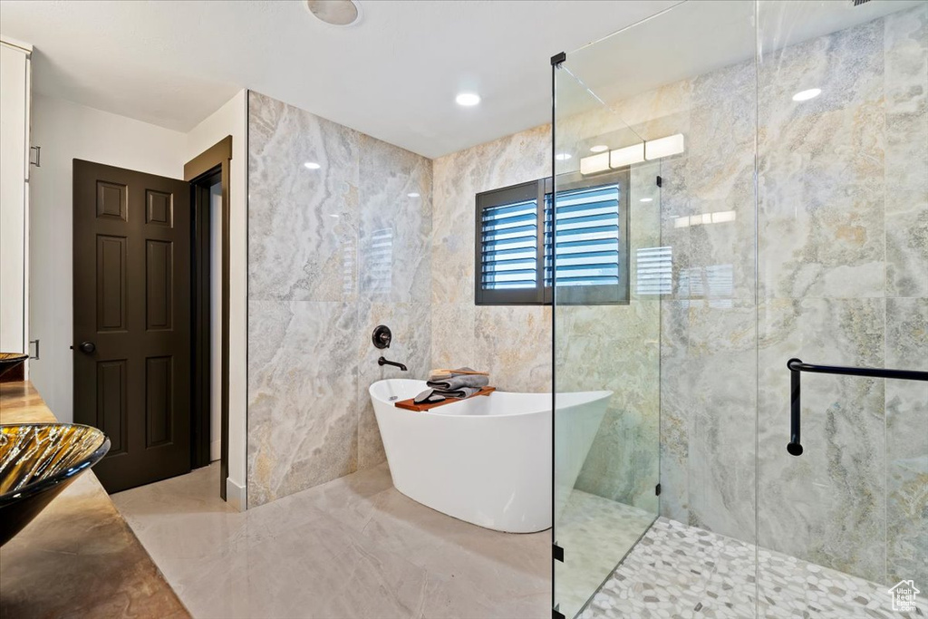 Bathroom featuring tile floors, independent shower and bath, and tile walls
