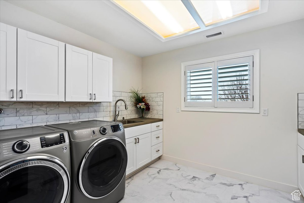 Laundry room featuring sink, cabinets, separate washer and dryer, and light tile floors