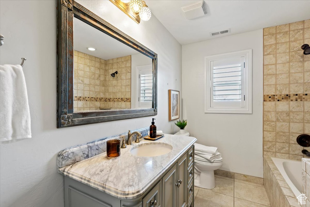 Full bathroom featuring tiled shower / bath combo, vanity, tile flooring, and toilet