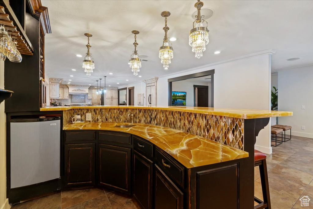 Kitchen featuring an inviting chandelier, a kitchen breakfast bar, dark tile floors, and dark brown cabinets