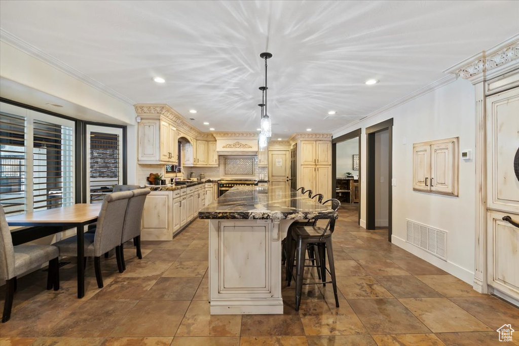 Kitchen with tile floors, a breakfast bar, ornamental molding, and a kitchen island