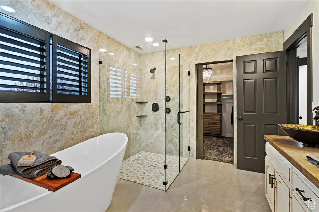 Bathroom featuring plus walk in shower, tile walls, vanity, and tile flooring