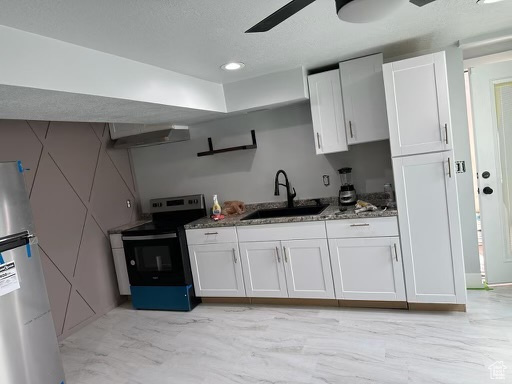 Kitchen with ceiling fan, white cabinetry, sink, electric range oven, and stainless steel refrigerator