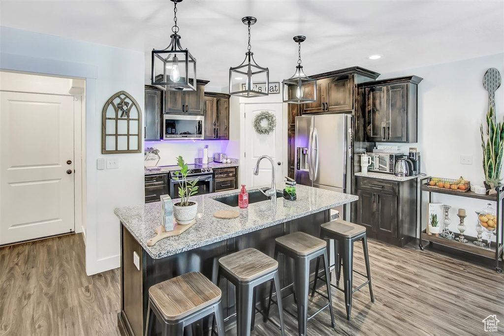 Kitchen featuring sink, stainless steel appliances, light hardwood / wood-style floors, and decorative light fixtures