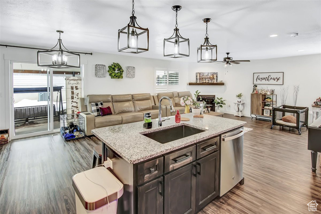 Kitchen featuring ceiling fan with notable chandelier, pendant lighting, light hardwood / wood-style flooring, stainless steel dishwasher, and sink