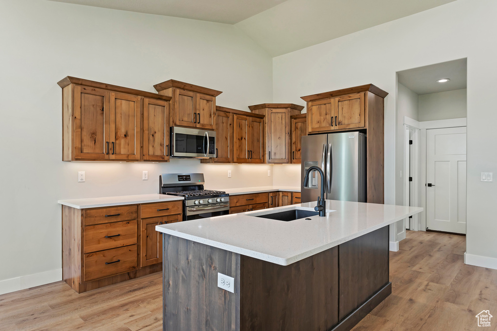 Kitchen with sink, a center island with sink, appliances with stainless steel finishes, and light hardwood / wood-style flooring
