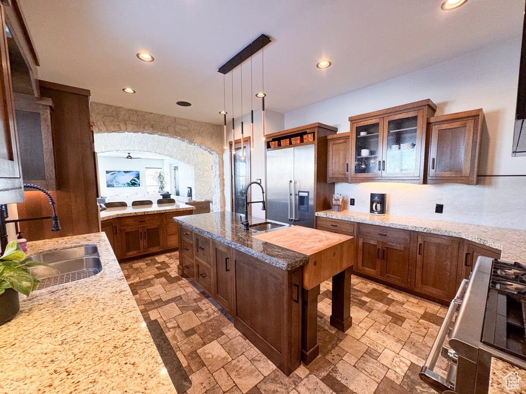 Kitchen featuring sink, high end fridge, pendant lighting, and light stone countertops