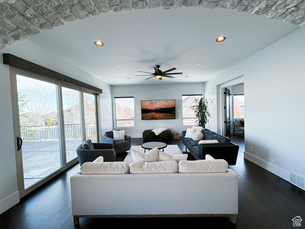Living room with dark hardwood / wood-style floors, ceiling fan, and plenty of natural light