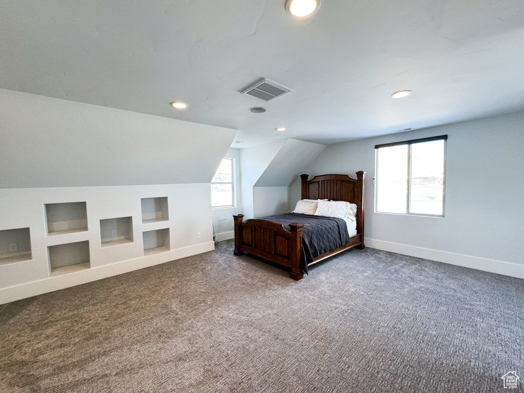 Unfurnished bedroom with lofted ceiling and dark carpet