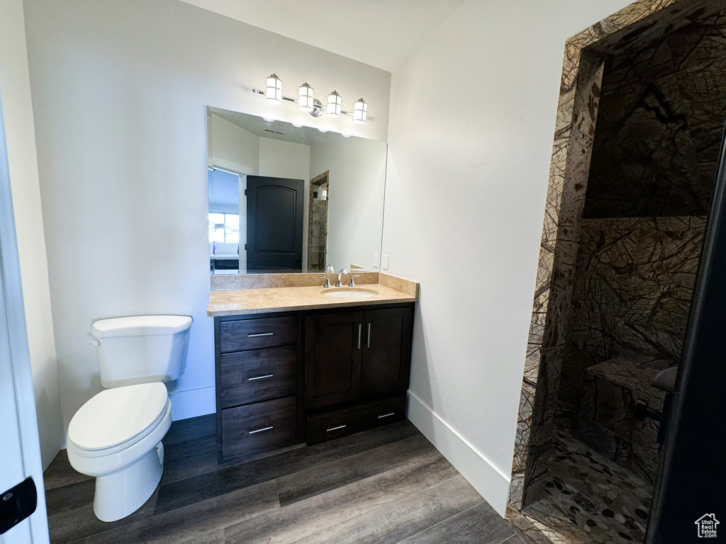 Bathroom featuring vanity, toilet, a shower, and hardwood / wood-style flooring