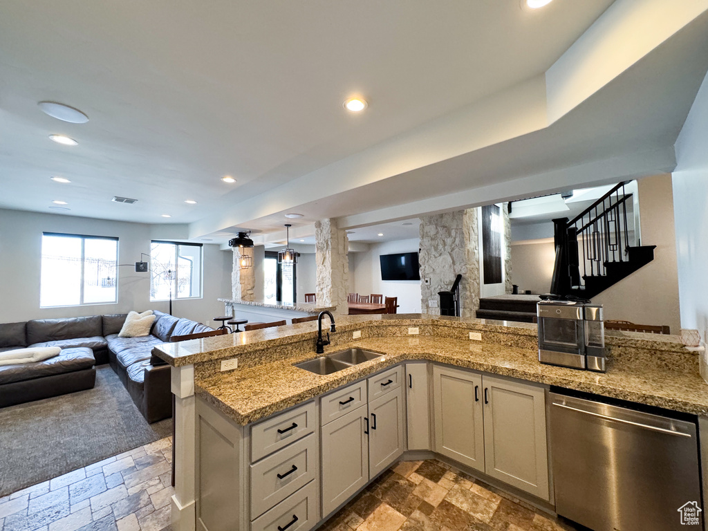 Kitchen featuring sink, stainless steel dishwasher, light stone counters, and light tile floors