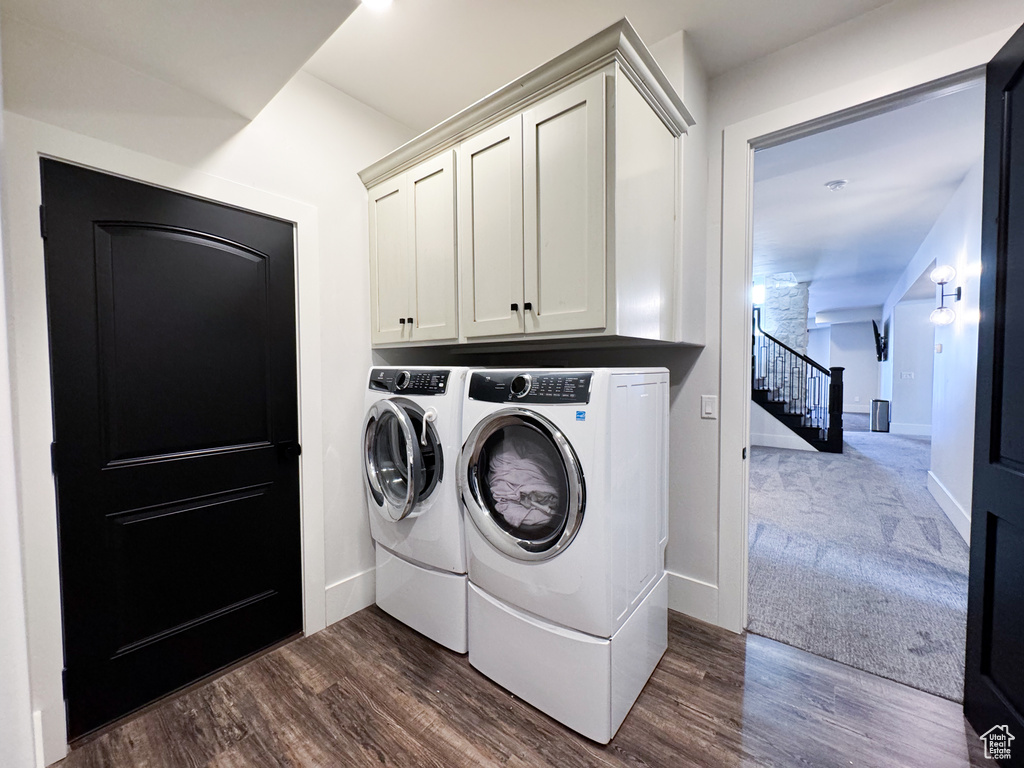 Washroom with dark hardwood / wood-style flooring, separate washer and dryer, and cabinets