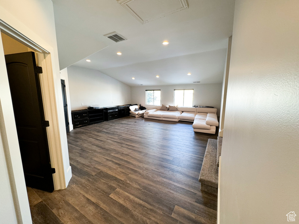 Unfurnished living room featuring dark hardwood / wood-style floors and vaulted ceiling