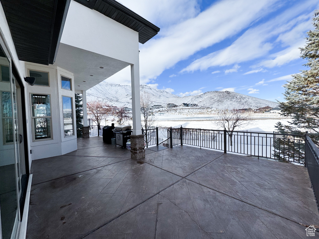 Snow covered patio featuring a balcony and a mountain view