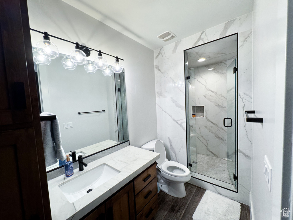 Bathroom with hardwood / wood-style floors, toilet, large vanity, and walk in shower