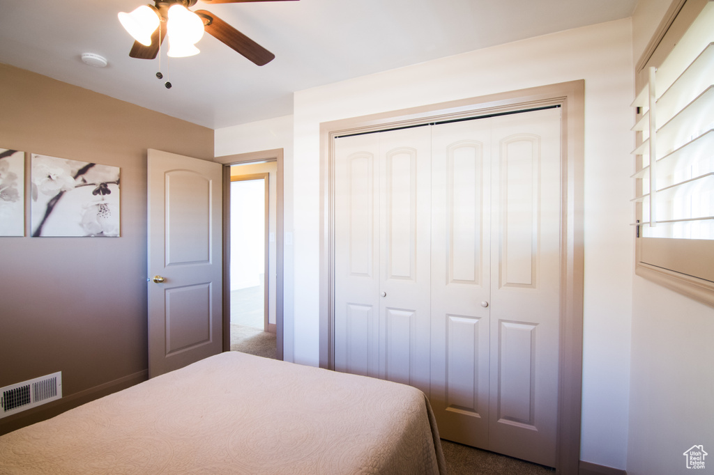 Bedroom featuring a closet, dark colored carpet, and ceiling fan