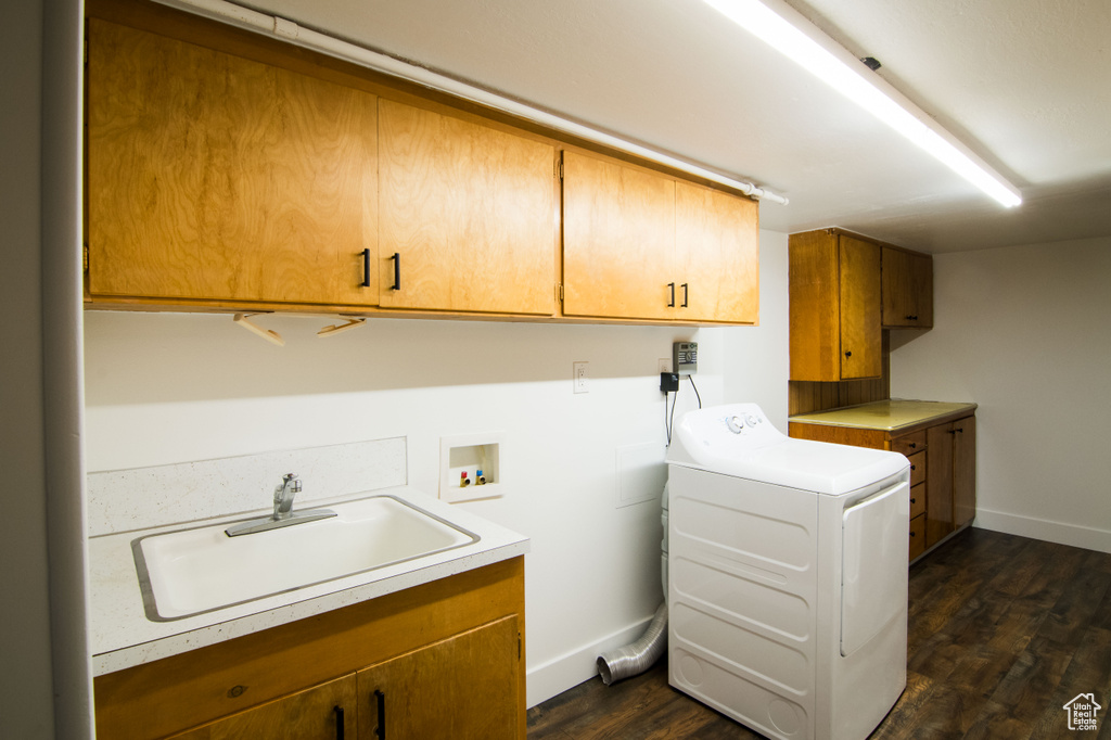 Clothes washing area featuring dark hardwood / wood-style floors, washer / clothes dryer, sink, and cabinets