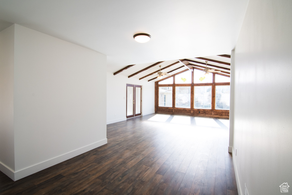 Empty room featuring dark hardwood / wood-style floors, a notable chandelier, and lofted ceiling with beams