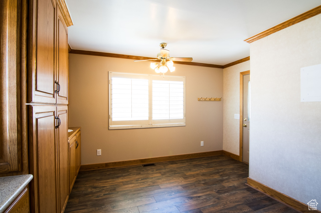 Empty room featuring dark hardwood / wood-style floors, ceiling fan, and ornamental molding