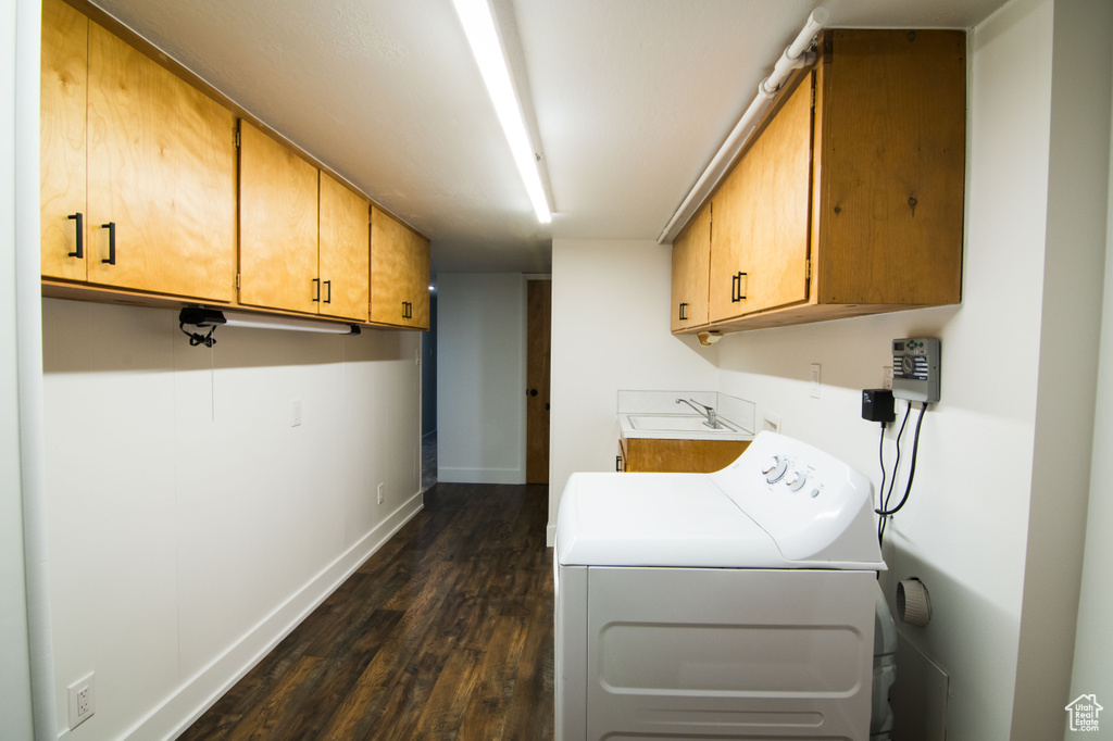 Clothes washing area with washer / dryer, dark hardwood / wood-style flooring, cabinets, and sink