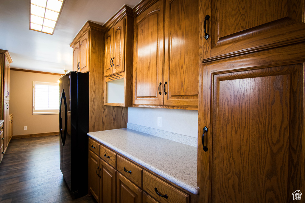 Kitchen featuring dark hardwood / wood-style flooring, black refrigerator, and crown molding