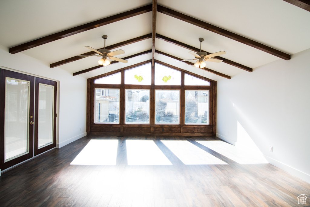 Unfurnished living room with dark wood-type flooring, ceiling fan, lofted ceiling with beams, and french doors