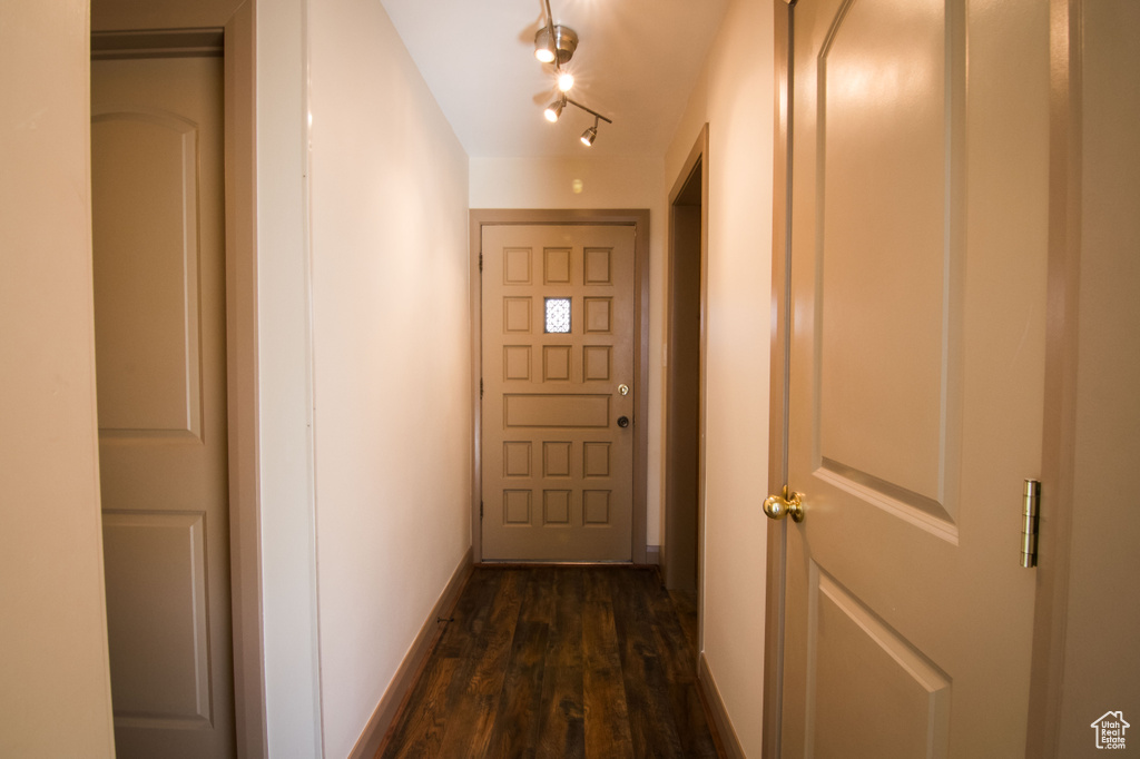 Doorway with dark hardwood / wood-style flooring and track lighting