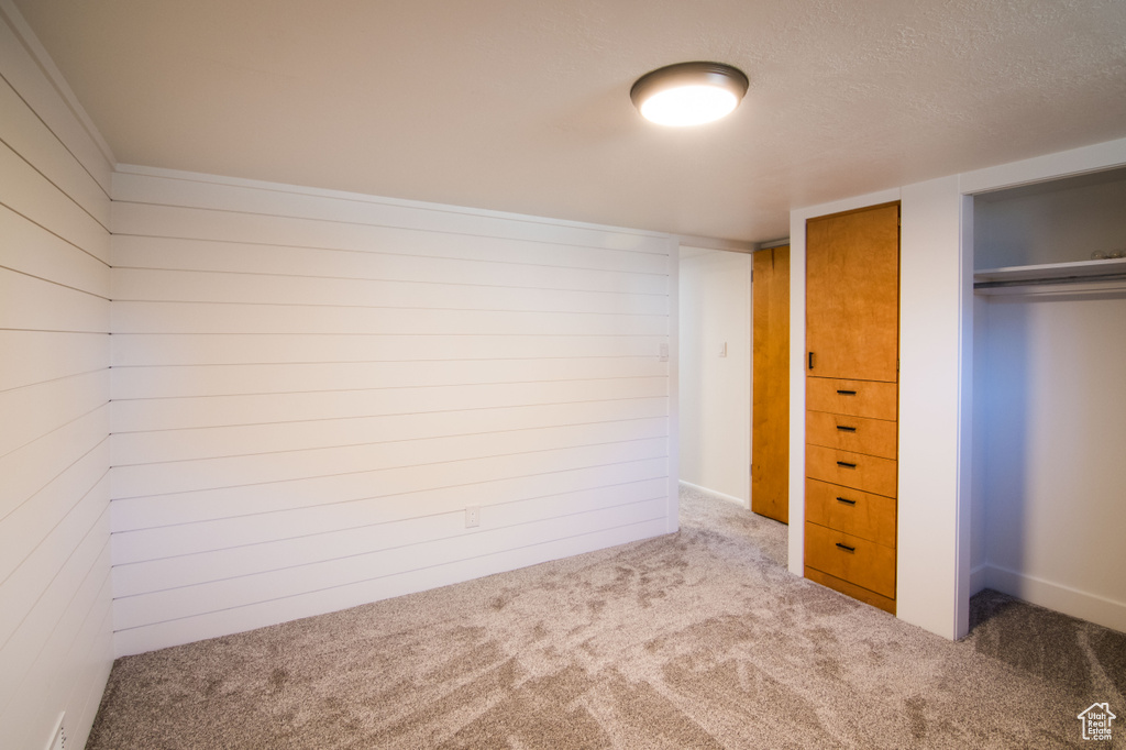Unfurnished bedroom with a closet, dark colored carpet, and a textured ceiling