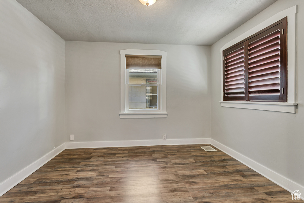 Empty room with dark hardwood / wood-style flooring and a textured ceiling
