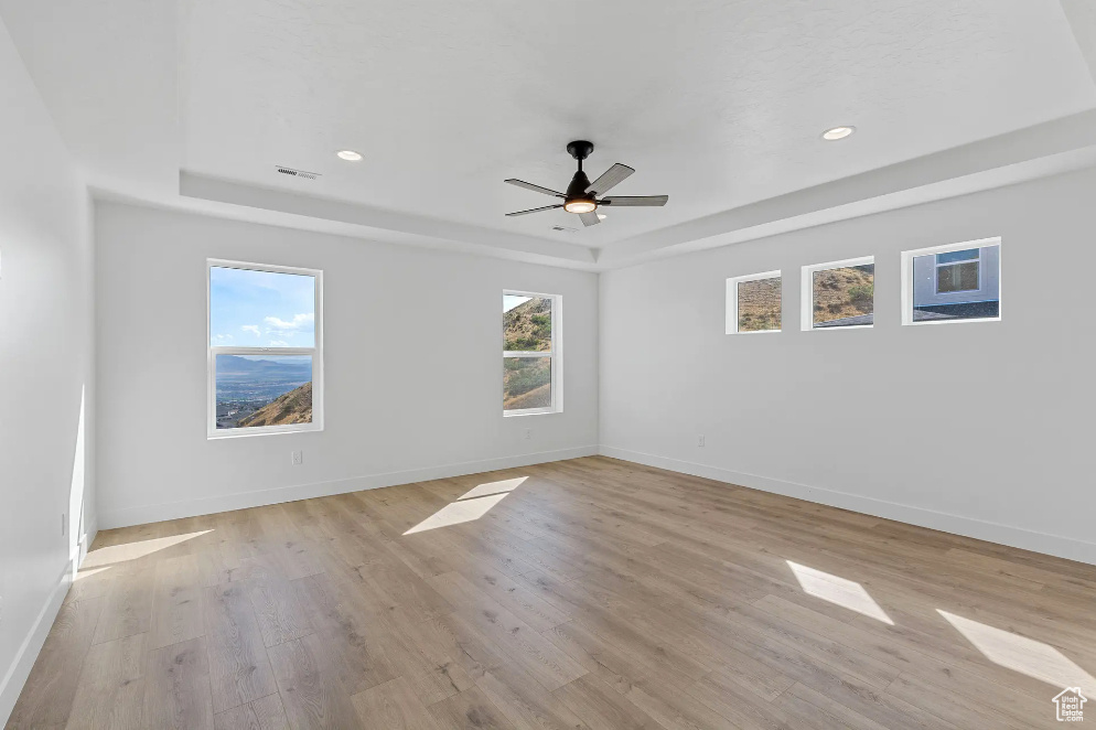 Empty room featuring a wealth of natural light, light hardwood / wood-style flooring, and ceiling fan