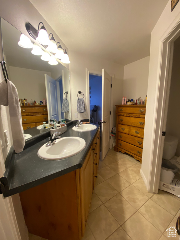 Bathroom with tile floors, double sink vanity, and toilet