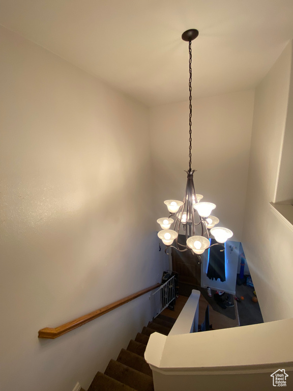 Stairs featuring wood-type flooring and a notable chandelier