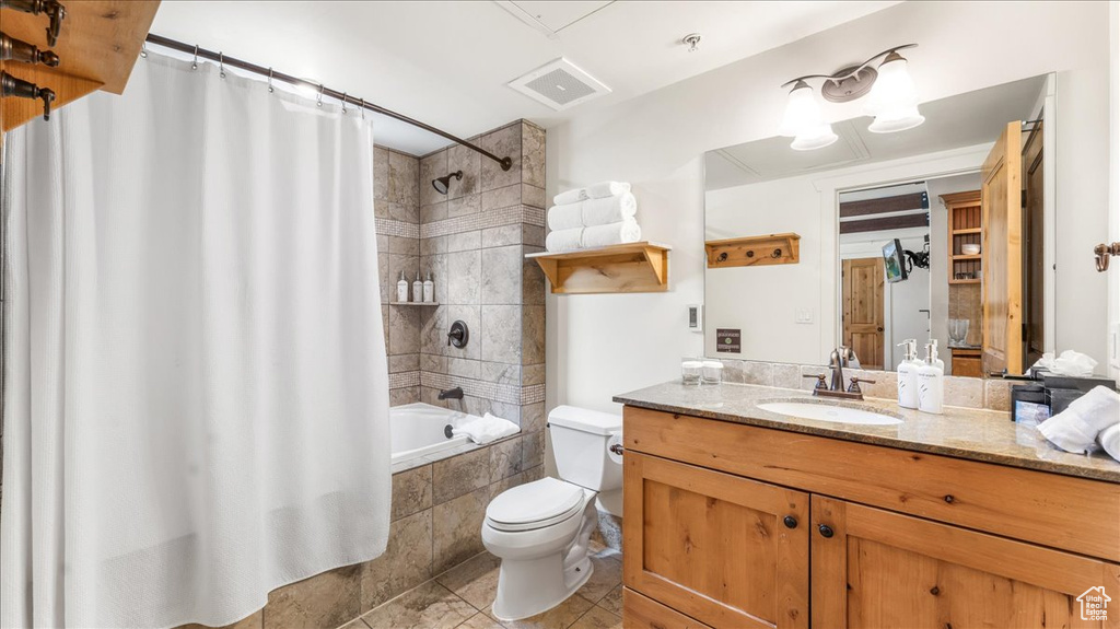 Full bathroom featuring tile floors, shower / tub combo, toilet, and vanity