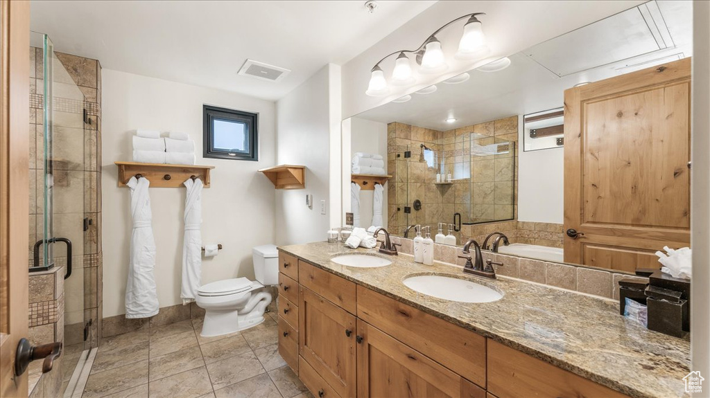 Bathroom featuring tile floors, an enclosed shower, toilet, and double sink vanity