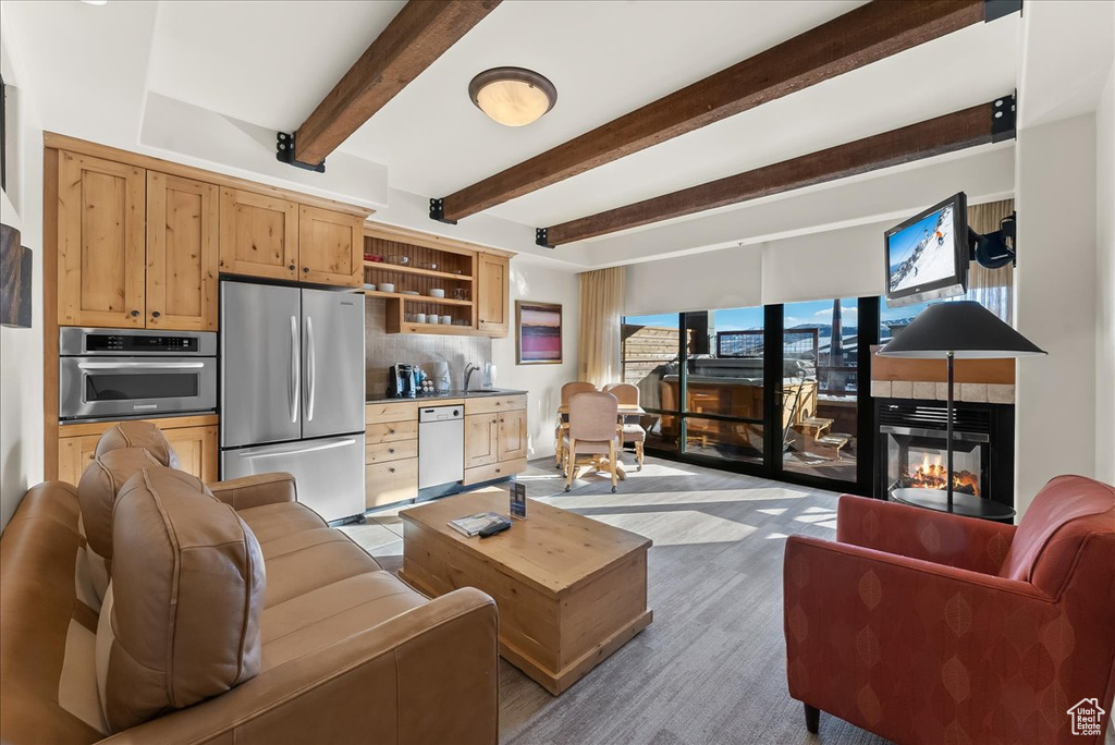 Living room featuring beam ceiling, sink, and light hardwood / wood-style floors