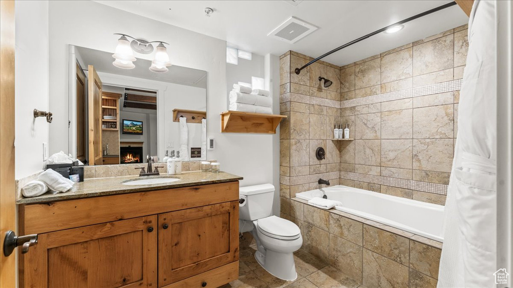 Full bathroom with tile floors, toilet, vanity, and shower / bath combo with shower curtain