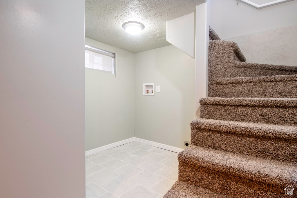Staircase featuring a textured ceiling and light tile floors