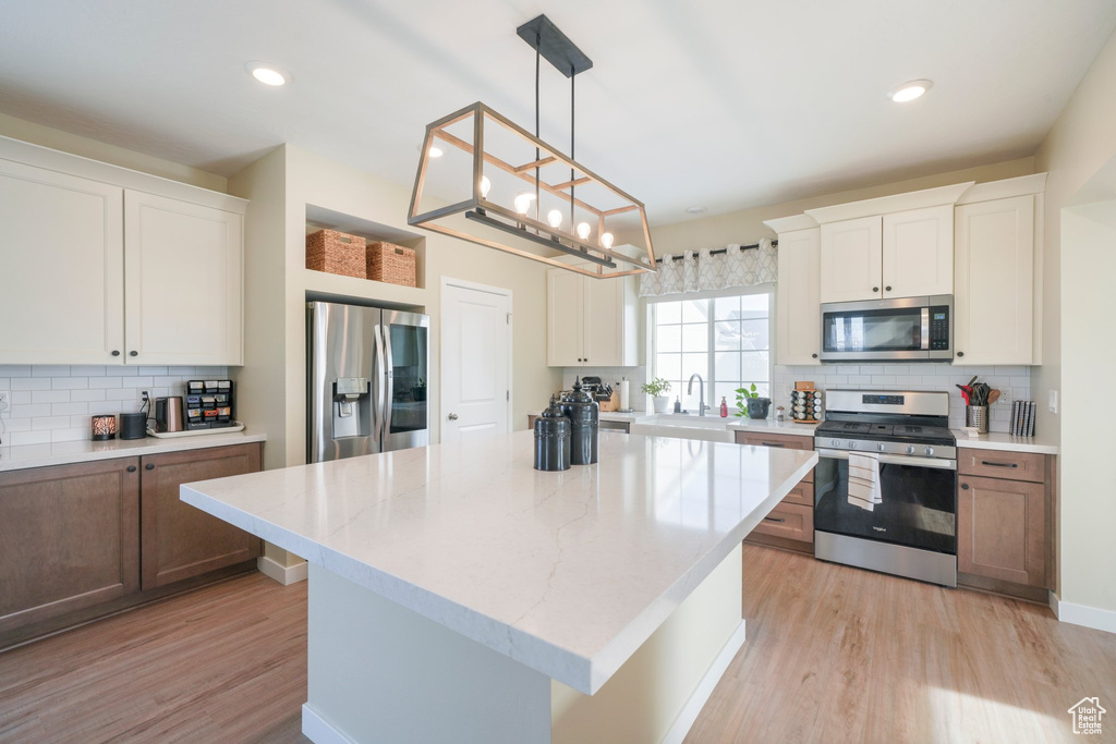 Kitchen featuring stainless steel appliances, a kitchen island, and white cabinetry