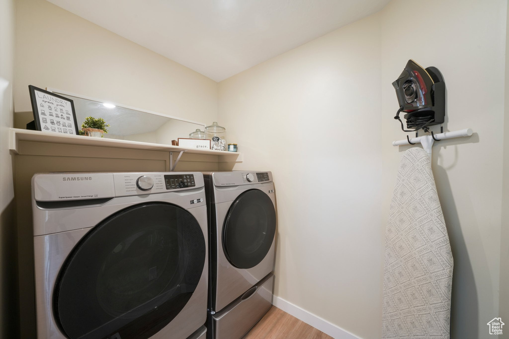 Washroom featuring washing machine and clothes dryer and light hardwood / wood-style floors