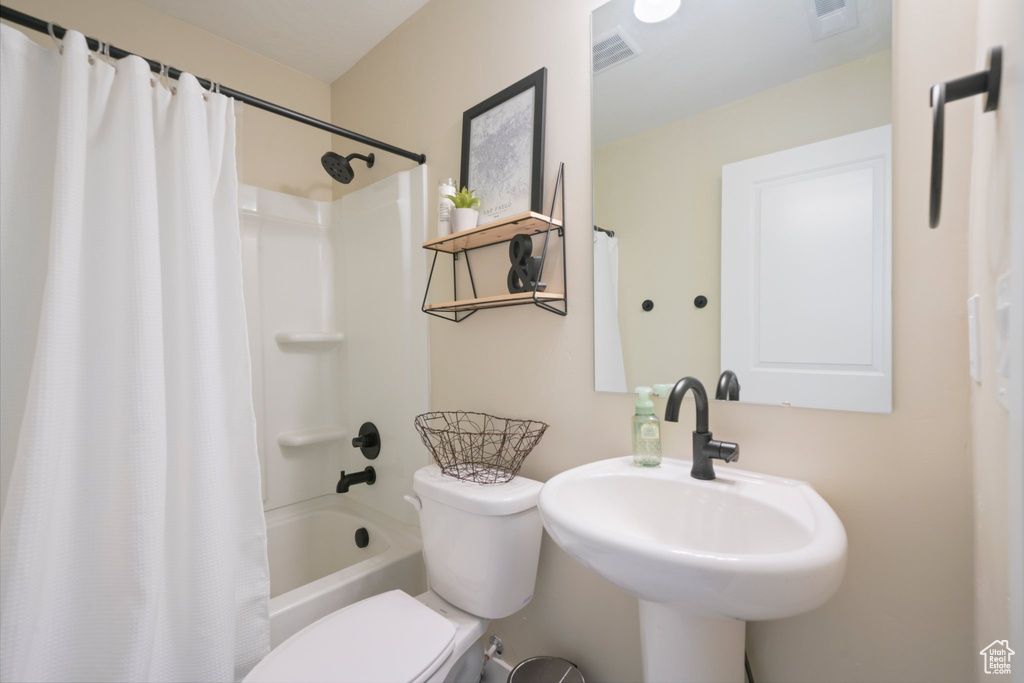 Full bathroom with sink, toilet, and shower / bath combo with shower curtain