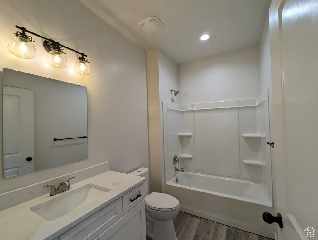 Full bathroom with wood-type flooring, vanity,  shower combination, and toilet